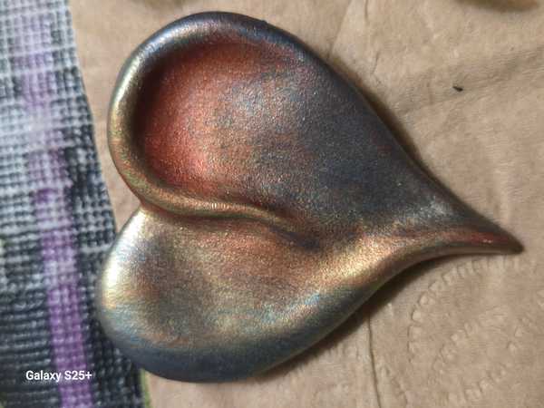 Iridescent Copper and Gray Heart Pendant on Beige Surface